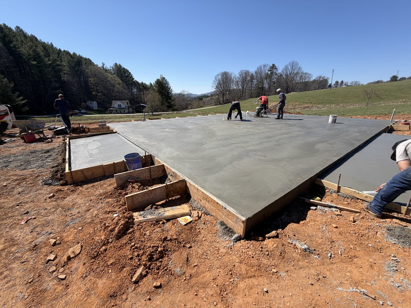 Riverfront Group crew finishing a freshly poured concrete slab foundation in Ashe County, NC