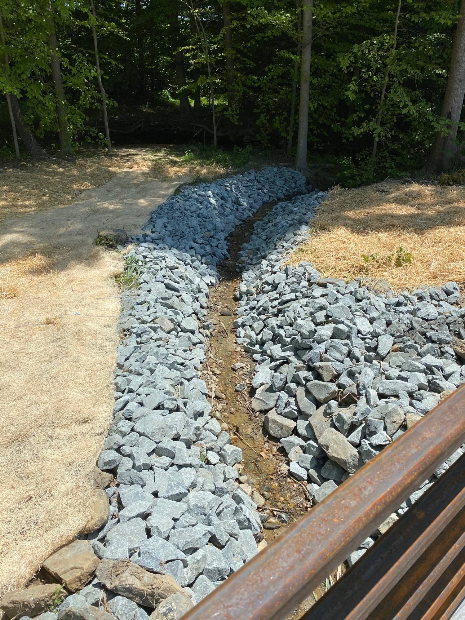 French drain and riprap drainage channel installed by Riverfront Group to control runoff on a wooded property in West Jefferson, NC
