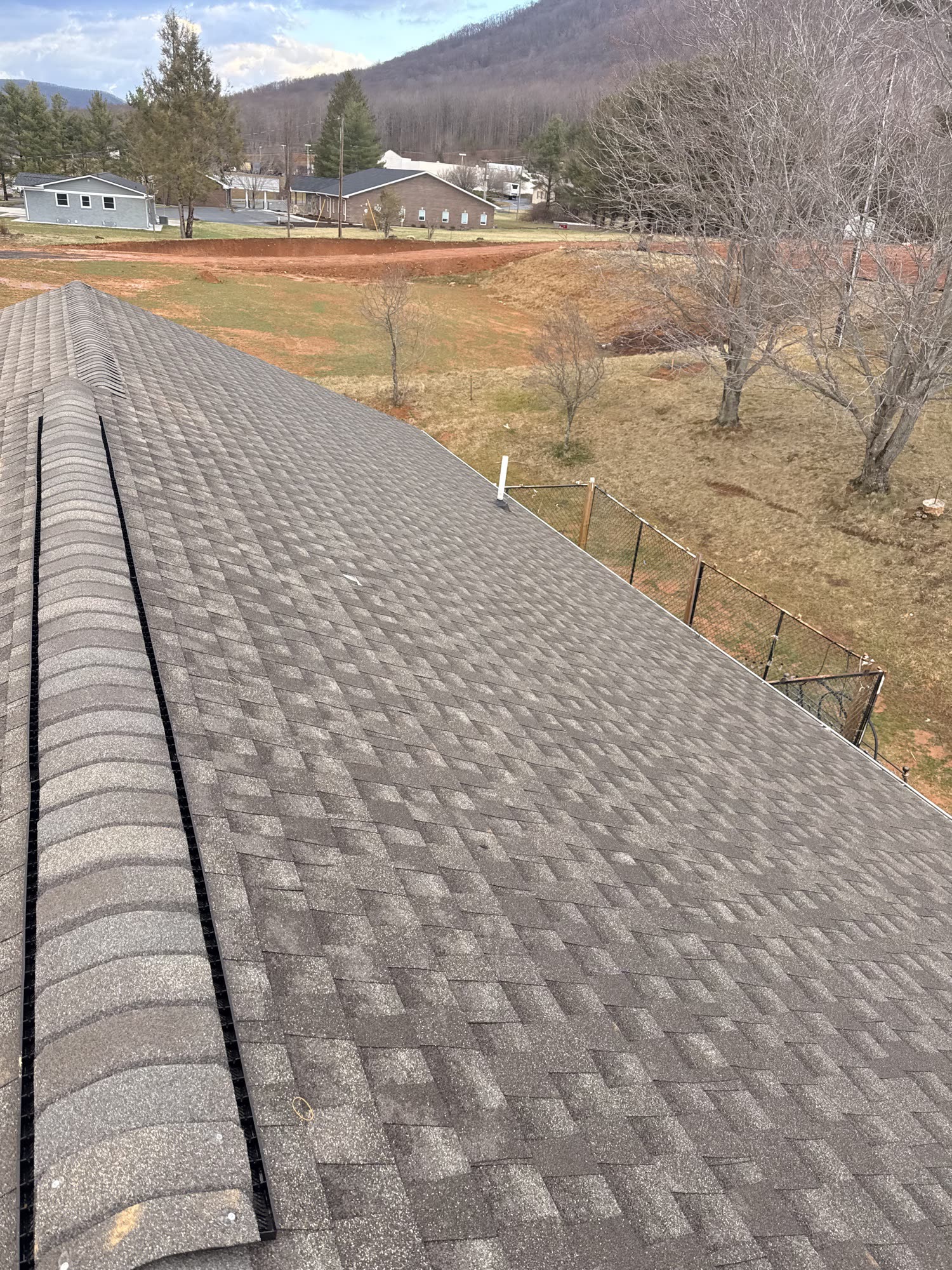 Completed asphalt shingle roof with ridge vent installed by Riverfront Group, overlooking the Ashe County High Country